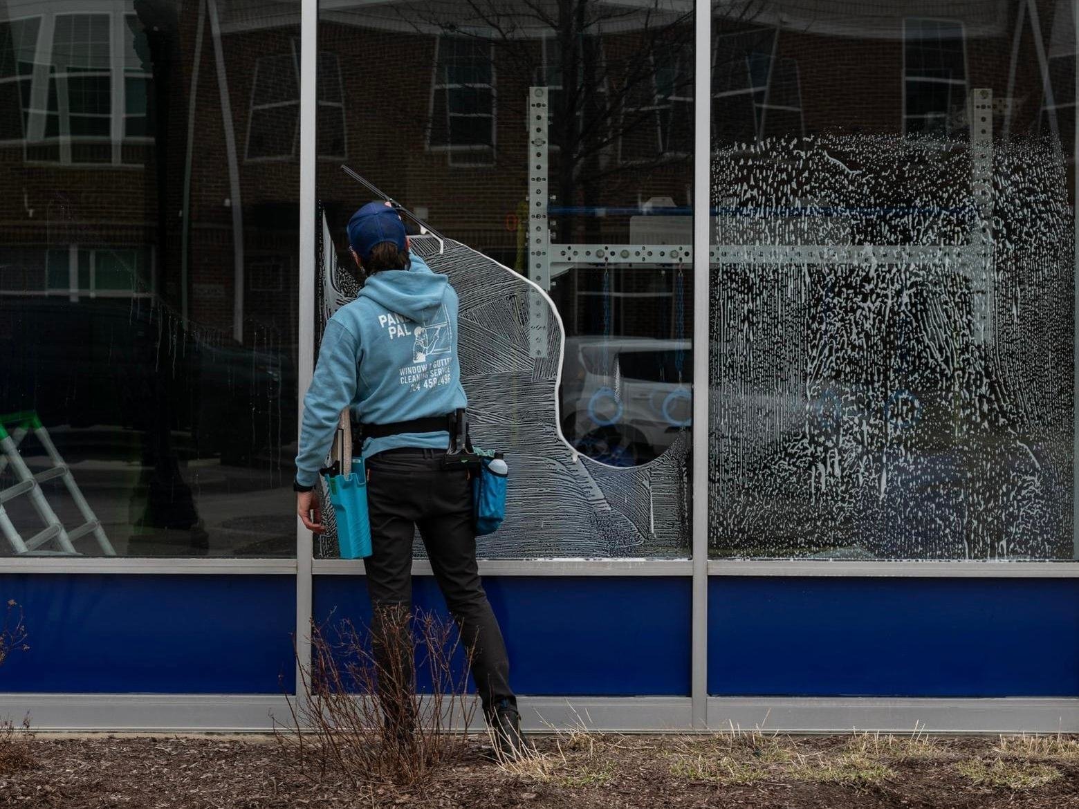 Pane Pal technician cleaning large building windows with professional equipment